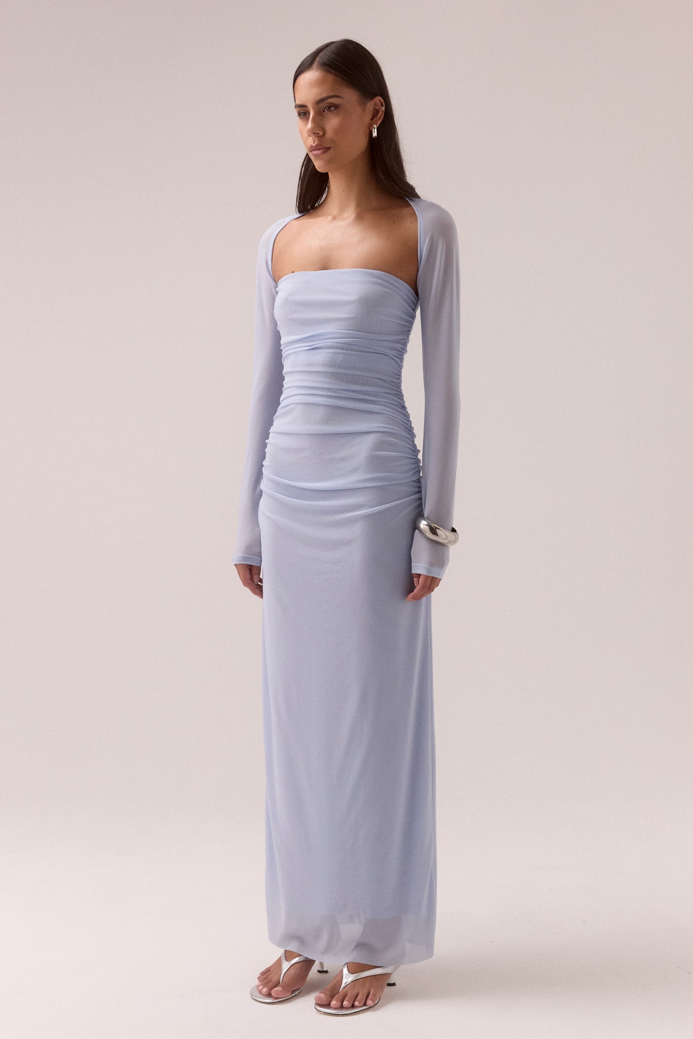 Model wearing SOVERE Studio Myriad Bolero Dress in Cool Blue, strapless mesh maxi with ruched sides and sheer bolero overlay