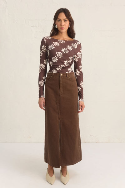 Model wearing the Mon Renn Bayside Denim Skirt in coffee — a high-waisted A-line brown denim midi skirt with a front split.