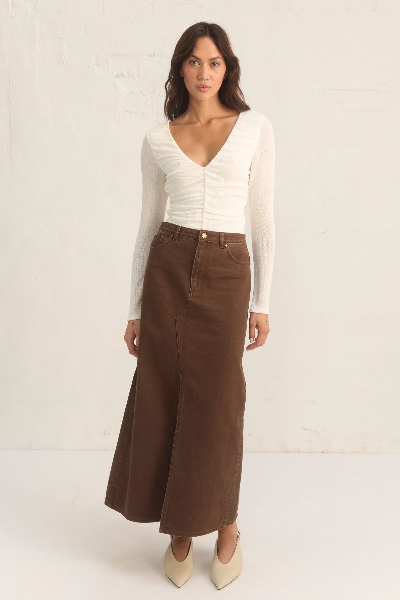 Model wearing the Mon Renn Bayside Denim Skirt in coffee — a high-waisted A-line brown denim midi skirt with a front split.