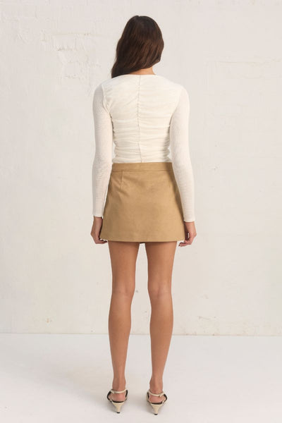 
Model wearing the Mon Renn Regenerated Top in cream — a deep V long-sleeve knit top with ruched sides and a body-skimming fit.
