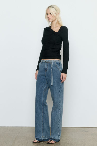 Model wearing the SOVERE Studio Solstice Top in black — a fitted, long-sleeve stretch top with an asymmetrical neckline.