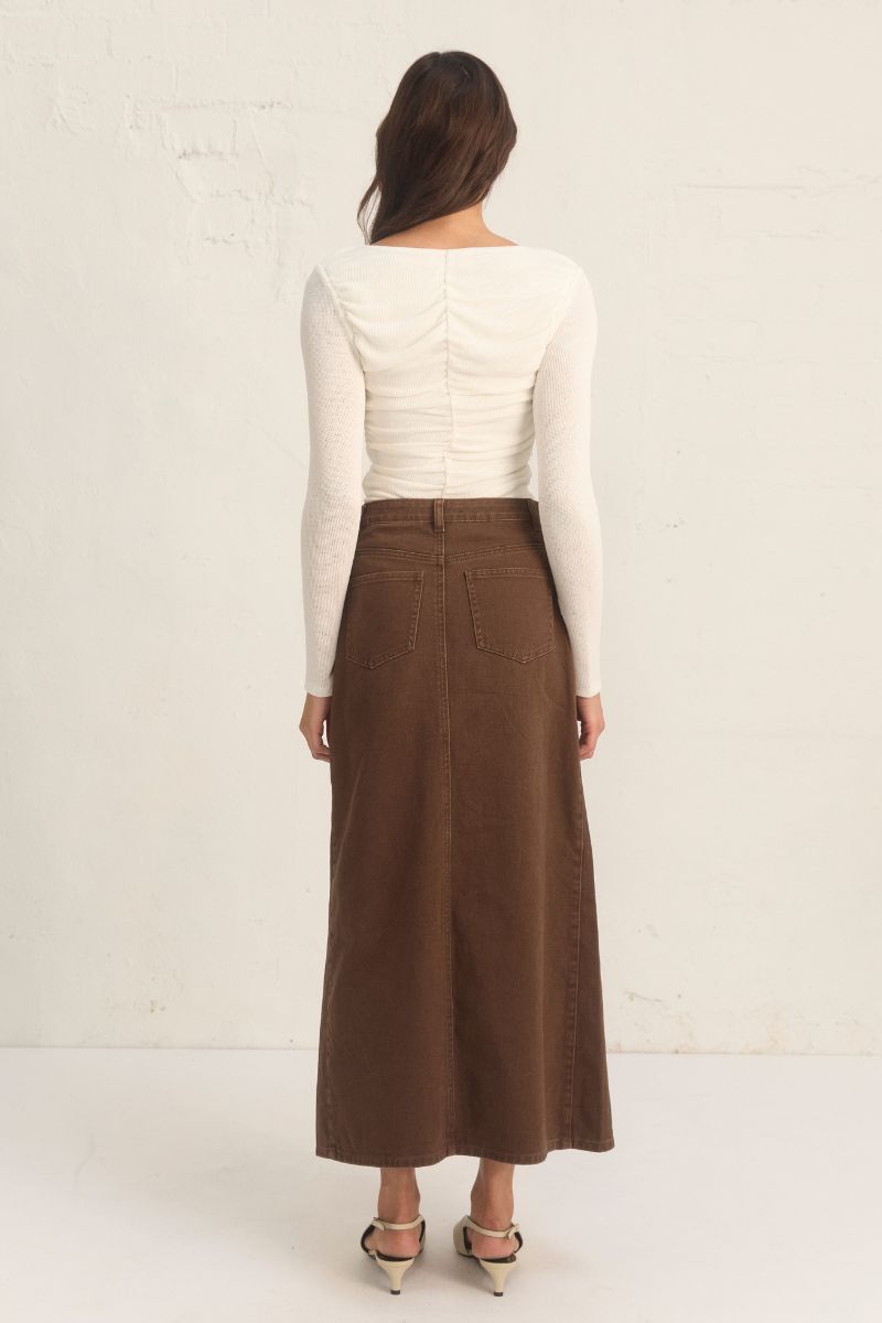 Model wearing the Mon Renn Bayside Denim Skirt in coffee — a high-waisted A-line brown denim midi skirt with a front split.