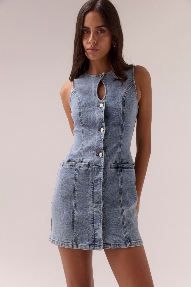 Model wears the SOVERE Studio Etch Denim Mini Dress featuring a sleeveless cut, crew neck with keyhole, and body-contouring panels.