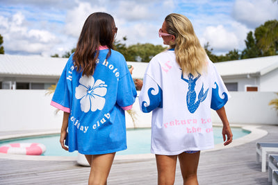 Oversized Hibiscus Hotel Mermaids Only Lounge Tee in white with bold blue graphics, styled for poolside.